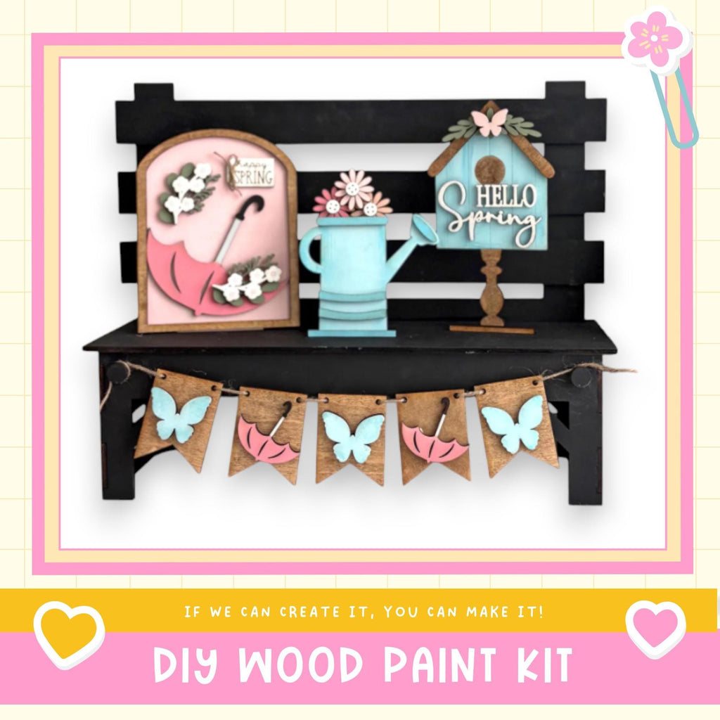 a DIY wood paint kit for creating a spring-themed decoration, including a wooden bench with a pink umbrella, a blue watering can, and a birdhouse. The kit is designed to allow users to create their own spring-themed decorations.