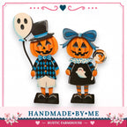two wooden Halloween figurines, a pumpkin and a ghost, standing together.