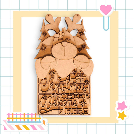 A wooden Christmas decoration with a reindeer and snowflakes, featuring the text &quot;Christmas cheer welcome here&quot; carved into it.