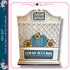 a decorative wooden sign with a lattice pattern, a blue pumpkin, and sunflowers, along with the text "Hello Autumn".