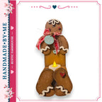 A handcrafted gingerbread man figure with a candle in its lap, set against a white background.