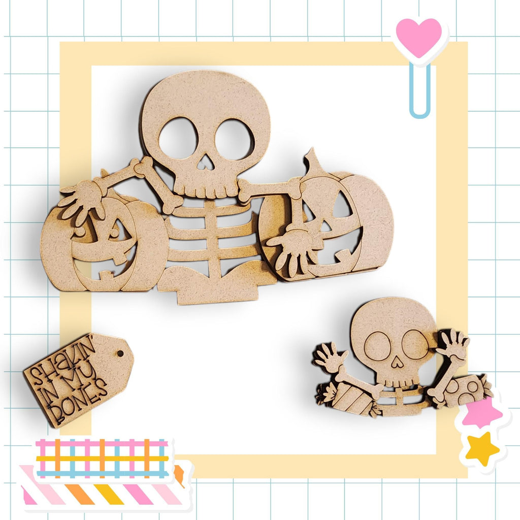 a Halloween-themed collage with various wooden cutouts, including a skeleton holding a carved pumpkin, a smaller carved pumpkin, and a carved pumpkin. The collage is set against a grid background with a heart and a star decoration.