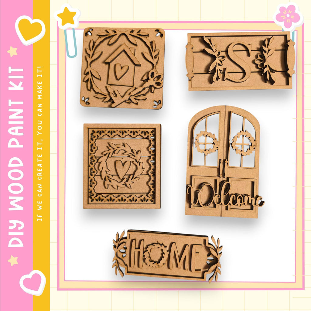 various wooden shapes and designs, including a house, a wreath, and a welcoming sign, all of which appear to be part of a DIY paint kit.