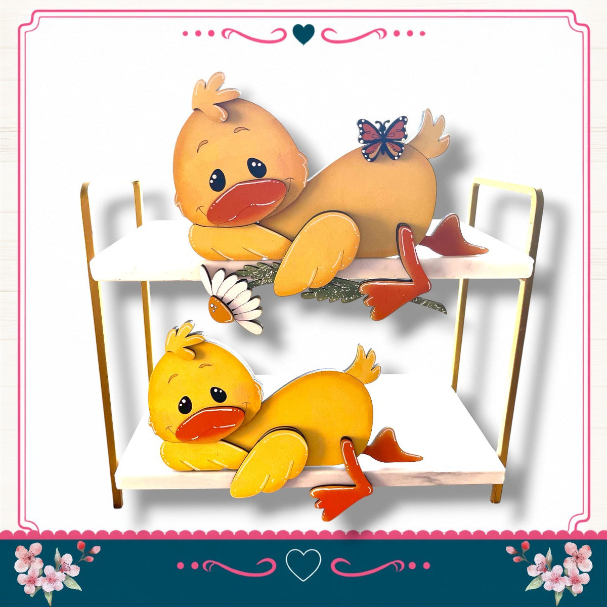 A cheerful scene featuring two cheerful yellow duck figures, one sitting on a white surface and the other lying down, with a flower decoration in the background.