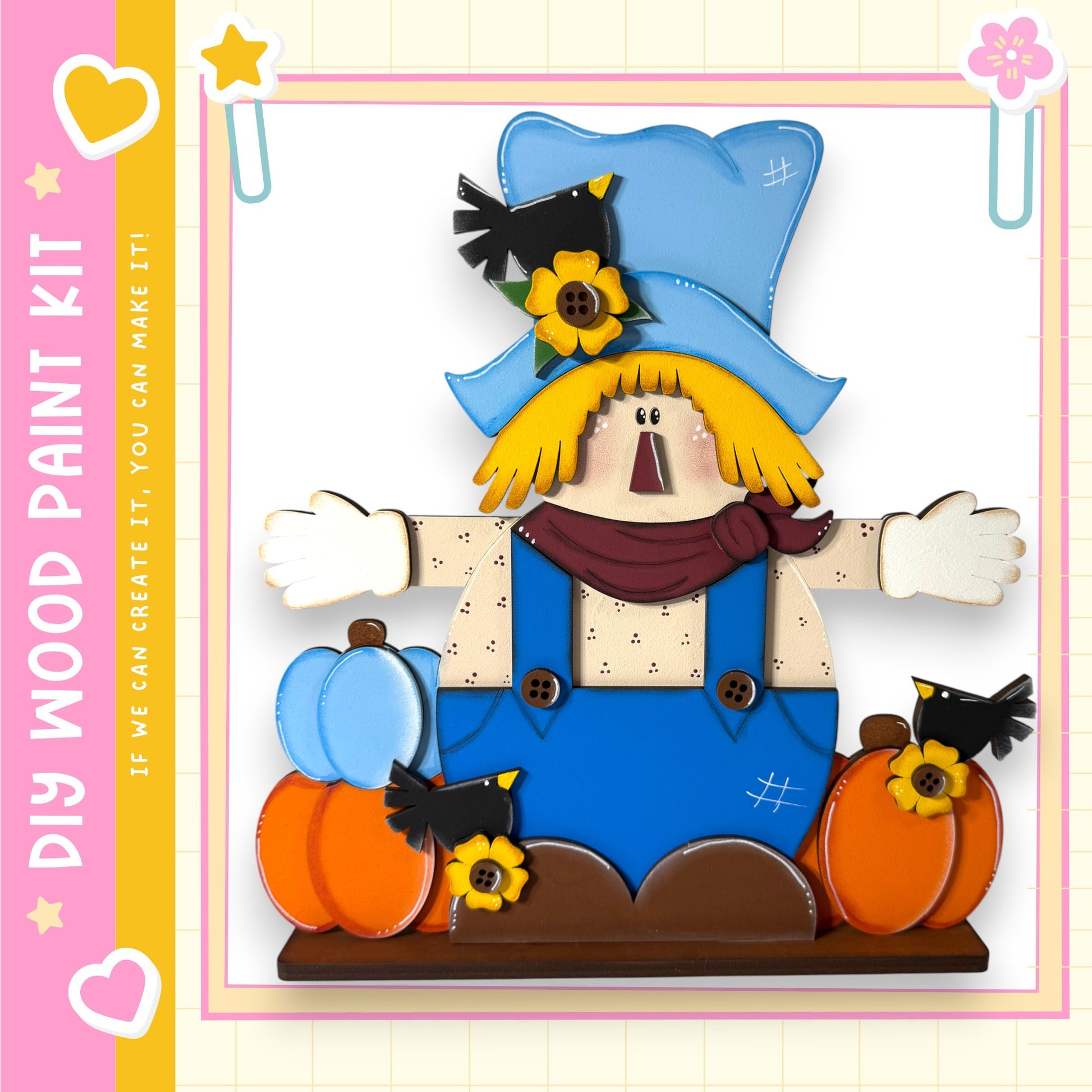 A colorful and whimsical illustration of a scarecrow figure, featuring a blue hat, a red scarf, and a pair of blue overalls. The scarecrow is holding two pumpkins and has a bird perched on its shoulder. The image is framed by a pink border and includes a heart and a star, creating a cheerful and festive atmosphere.