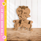 A wooden cutout of a witch sitting in a chair, holding a book titled "SPELLS".