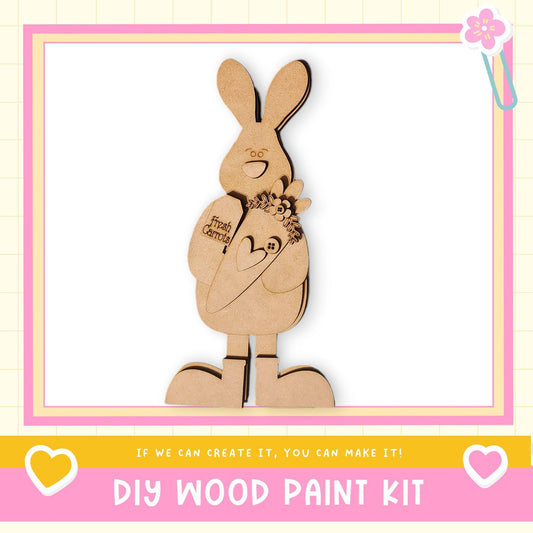 A wooden toy rabbit holding a flower, with a pink and yellow border and text promoting a DIY wood paint kit.