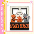 A spooky-themed wooden paint kit featuring a ghost, a cat, and pumpkins, with the text "SPOOKY SEASON" displayed on the kit.