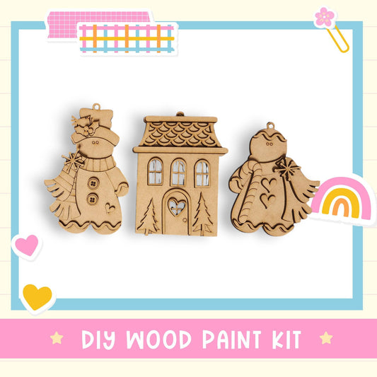 a DIY wood paint kit with three wooden ornaments, including a snowman, a house, and a heart-shaped ornament.
