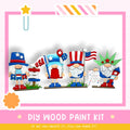 four wooden gnomes dressed in patriotic outfits, including hats and flags, standing together and holding signs. The text "DIY WOOD PAINT KIT" is displayed, along with the phrase "If we can create it, you can make it!"