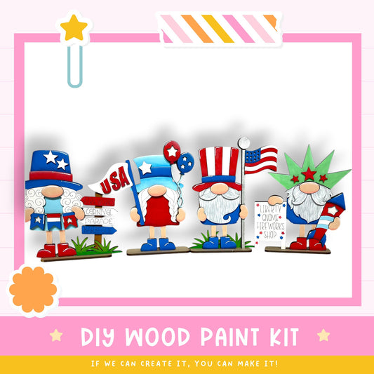 four wooden gnomes dressed in patriotic outfits, including hats and flags, standing together and holding signs. The text "DIY WOOD PAINT KIT" is displayed, along with the phrase "If we can create it, you can make it!"