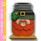 A whimsical, hand-painted jar with a leprechaun face design, including a green shamrock, a gold belt, and a red beard.