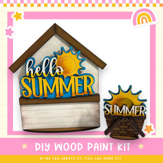 The image is a promotional poster for a DIY wood paint kit, featuring a wooden house with a "Hello Summer" sign and a small wooden basket with a "Summer" sign. The text on the poster encourages viewers to create their own designs with the kit, and the phrase "If we can create it, you can make it!" is displayed.