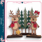 two wooden reindeer figures standing in front of a Christmas tree, with a candy cane and bell nearby.
