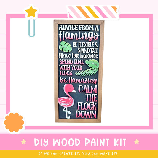 The image is a DIY wood paint kit advertisement for a craft project. It features a blackboard with colorful text and a pink border, along with a pink and orange striped frame. The text on the blackboard provides advice on how to create a flamingo-themed project, including tips on flexibility, balance, and relaxation.