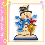 A wooden snowman figure with a bird perched on its roof, wearing a blue scarf and hat, and holding a birdhouse.