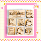 six wooden cutout shapes, each with a unique design and text, arranged in a grid-like pattern within a pink and yellow border.