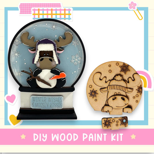 a DIY wood paint kit for creating a snow globe with moose kisses, including a snow globe with a moose and a wooden moose kisser.