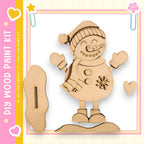 A wooden snowman kit with a smiling face, a carrot nose, and a scarf, along with a wooden stick and a heart-shaped cutout.