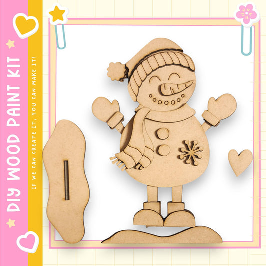 A wooden snowman kit with a smiling face, a carrot nose, and a scarf, along with a wooden stick and a heart-shaped cutout.