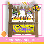 The image is a Halloween-themed DIY wood paint kit featuring a spooky wooden sign with the text "Boo Crew" and "Spookytown Home of the Boos". The sign is decorated with various Halloween-themed elements such as a ghost, a witch, and a candy cane. The kit appears to be designed for creating a spooky wooden sign or decoration for a Halloween-themed event or party.