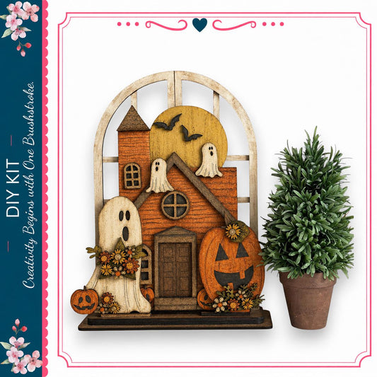 a Halloween-themed wooden house decoration with a carved pumpkin, ghost, and other spooky elements. The decoration is displayed next to a potted plant, creating a festive atmosphere.