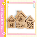 three wooden houses with various decorative elements, including hearts and text, arranged against a pink and yellow background.