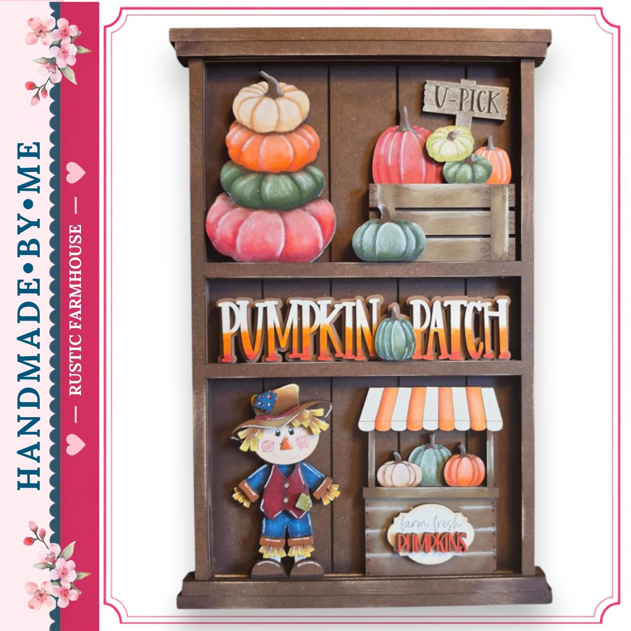 The image is a hand-made wooden pumpkin patch display featuring various autumn-themed elements such as pumpkins, a scarecrow, and a sign that reads "U-Pick".