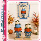 two decorative pumpkin planters with a stack of three pumpkins on top, placed on a wooden surface. The planters are adorned with blue and white ribbons, and there are vases of flowers and pumpkins in the background. The image also includes a framed sign with the word "Welcome" and a heart symbol, as well as a pink banner with the text "Handmade by Me Rustic Farmhouse".