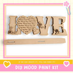 a DIY wood paint kit with the word "LOVE" made of wooden letters, along with a heart-shaped cutout and decorative elements.