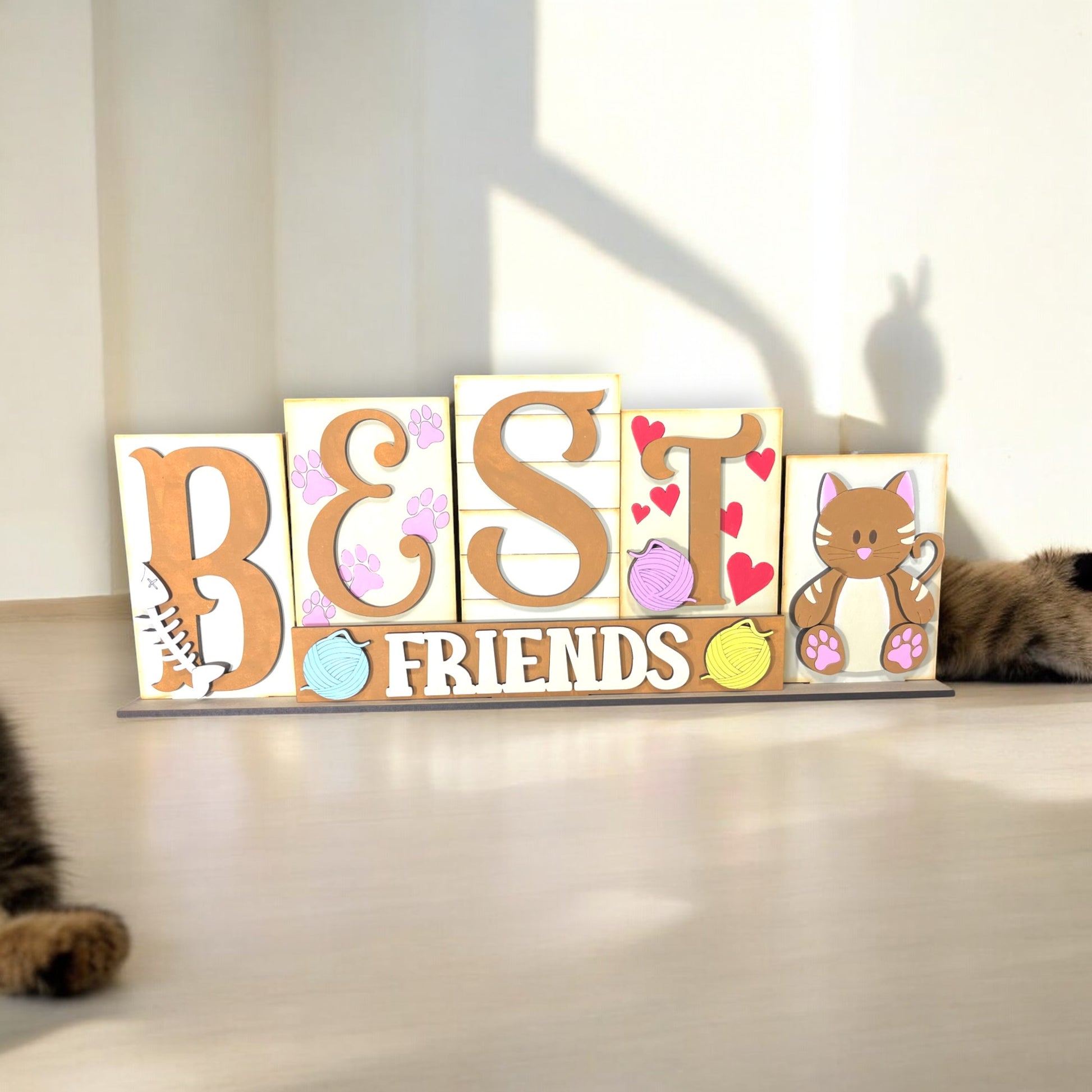 a cat laying on the floor next to a wooden block that says best friends