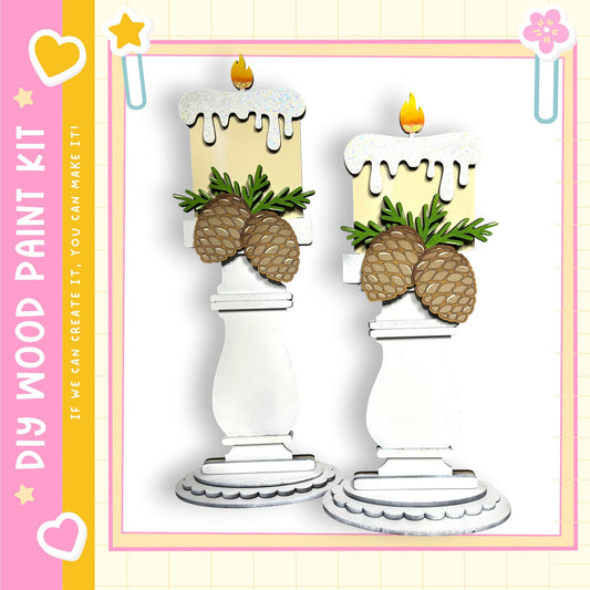 two white candle holders with pine cones and a candle on top, set against a pink and yellow background.