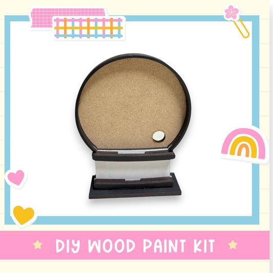a DIY wood paint kit, including a wooden frame with a blank center and a small white object inside. The kit is surrounded by various colorful stickers and hearts, creating a playful and creative atmosphere.