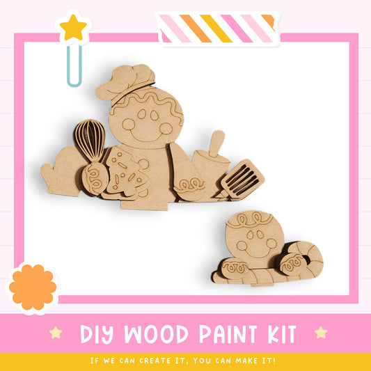 The image is a DIY wood paint kit featuring two wooden figures, one larger and one smaller, along with various kitchen utensils such as a whisk, spatula, and ladle. The kit appears to be made of wood and is designed for painting and decorating.