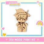 a DIY wood paint kit, including a wooden figure wearing a hat and bow, surrounded by various colorful stickers and illustrations.