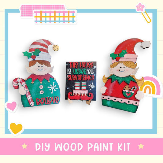 two wooden elf dolls, one holding a sign that says "This holiday is underappreciated", and the other holding a candy cane. The image also includes a DIY wood paint kit and a colorful background with various shapes and decorations.
