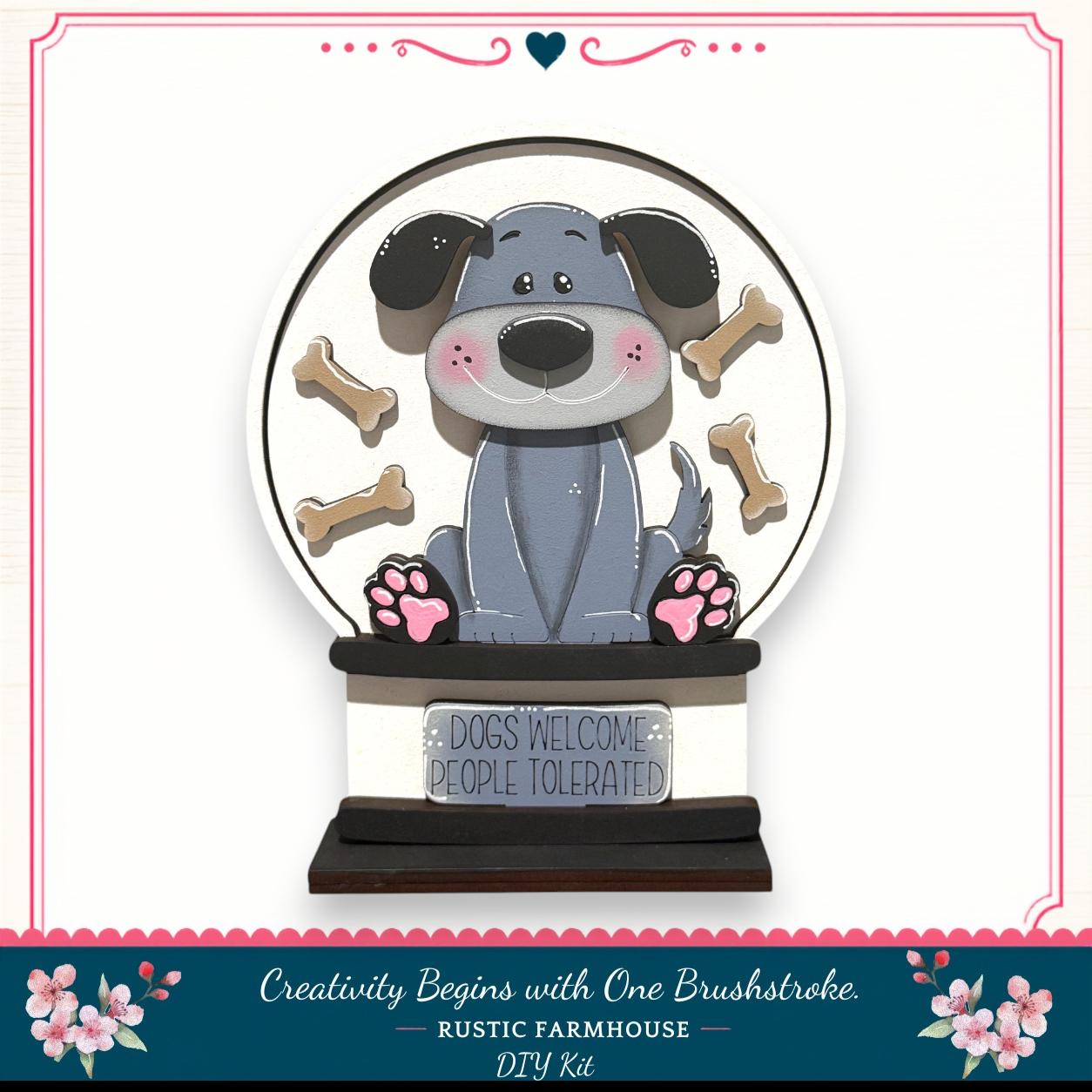 A wooden snow globe featuring a cartoon dog surrounded by dog bones, with a sign that says "Dogs Welcome People Tolerated".
