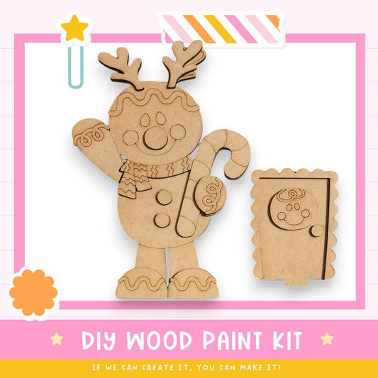 a DIY wood paint kit for creating a wooden gingerbread man. The kit includes a wooden gingerbread man figure and a wooden candy cane. The kit is presented in a pink and white color scheme, with a star decoration on the top left corner. The text "DIY WOOD PAINT KIT" is prominently displayed, along with the phrase "IF WE CAN CREATE IT, YOU CAN MAKE IT!" at the bottom of the image.