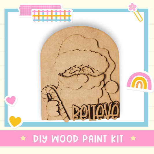 A DIY wood paint kit featuring a wooden Santa Claus figure with the word "Believe" written on it.