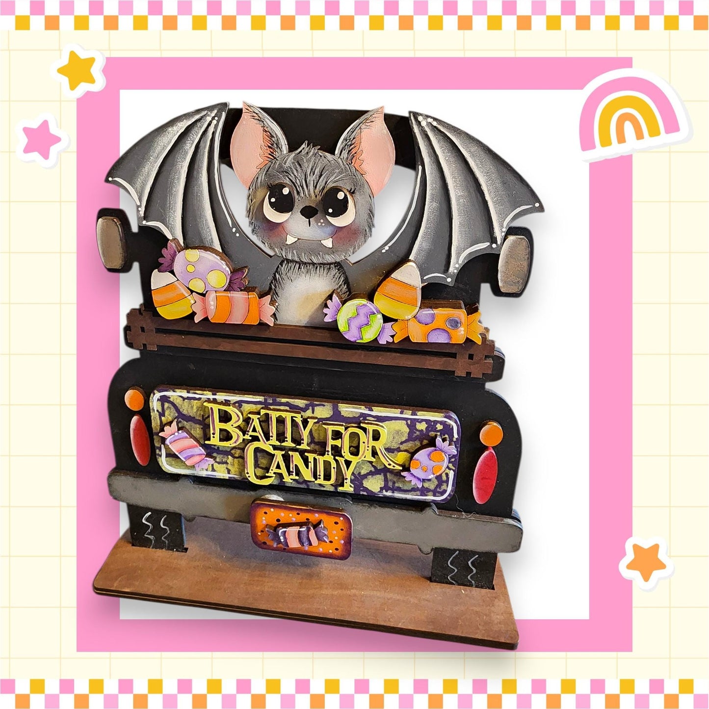 A wooden toy truck decorated with a bat and various candy items, including a sign that says "Bally for Candy".