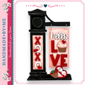 A handmade sign with the words "Hello Love" displayed on it, along with a cupcake and a heart. The sign is black and features decorative elements such as the word "XO" and the word "LOVE".