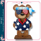 A wooden teddy bear wearing sunglasses and a patriotic outfit with stars and stripes, standing on a wooden base.