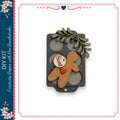 a wooden gingerbread man figure with a heart tag, placed on a black tray with a leaf decoration.