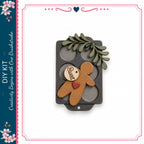 a wooden gingerbread man figure with a heart tag, placed on a black tray with a leaf decoration.