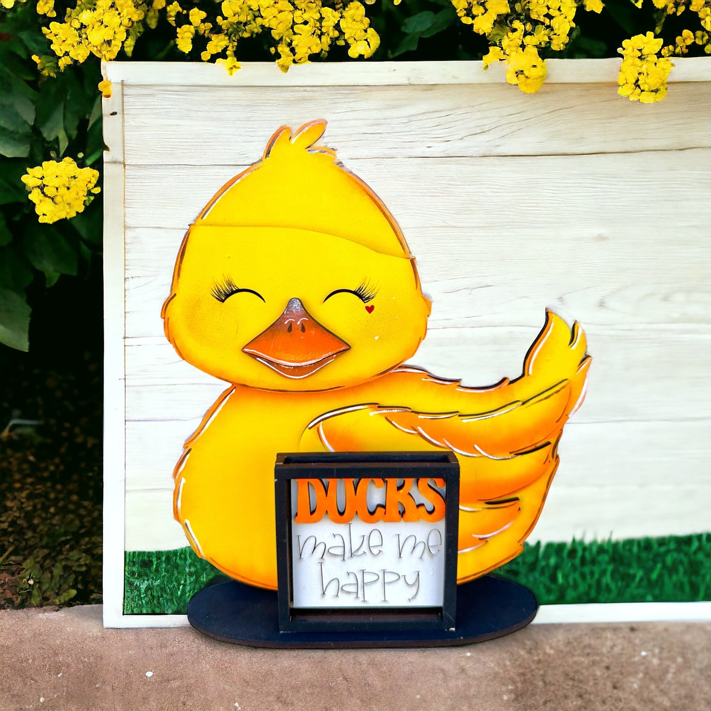 a picture of a yellow duck with a sign in front of it