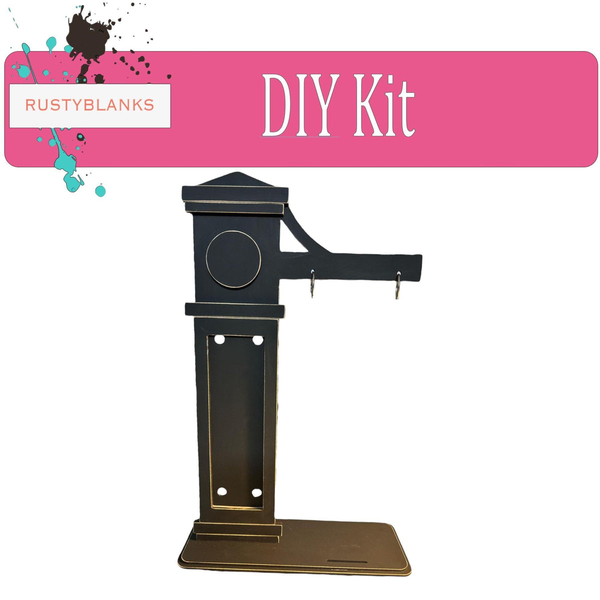 a DIY kit, which appears to be a black metal object with a circular design on the front. The kit is displayed against a pink background, and there is a small amount of splatter visible on the pink background.