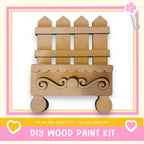 a DIY wood paint kit, with a wooden fence and decorative elements displayed.