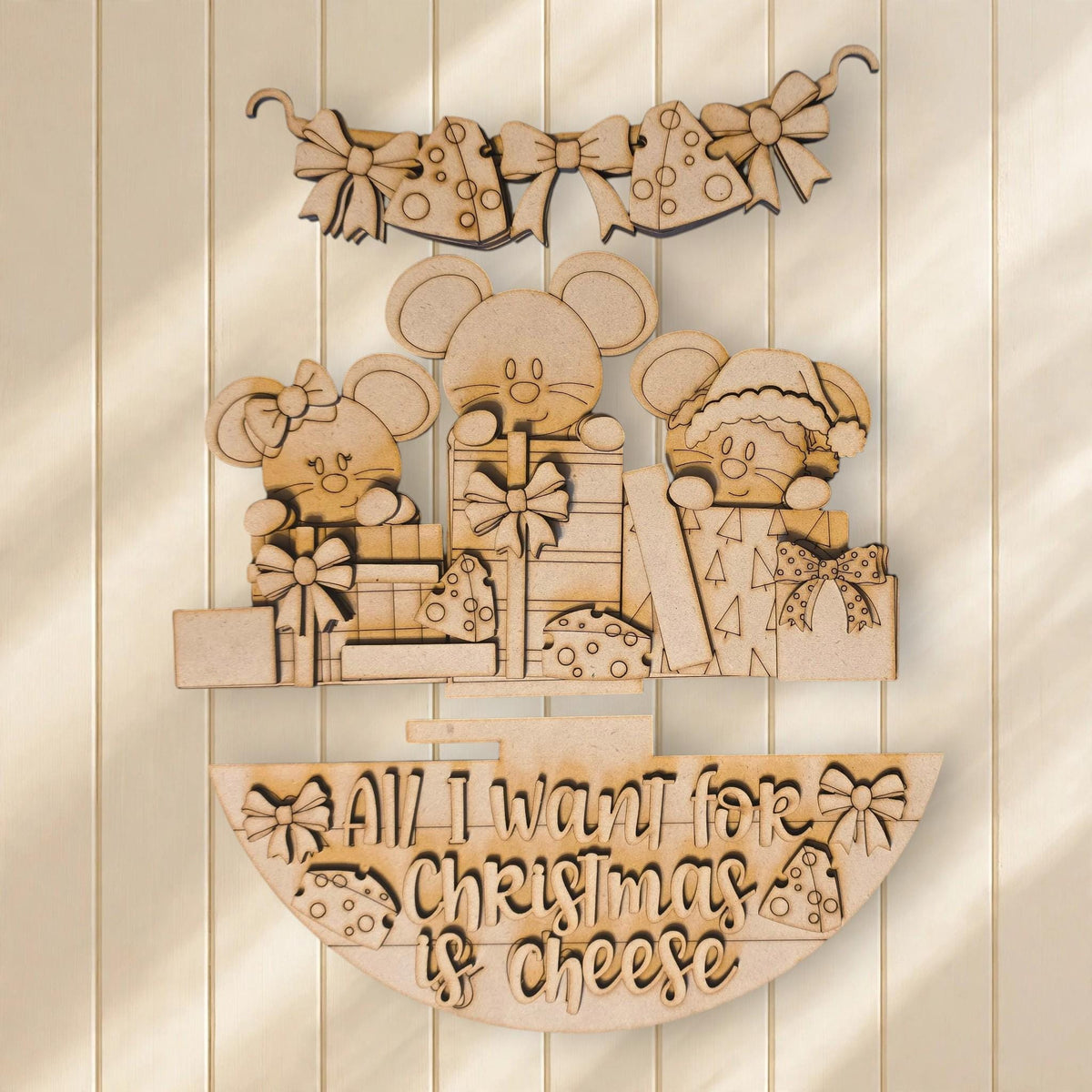 A wooden Christmas decoration with a playful design featuring cartoon mice and the text "All I want for Christmas is cheese".
