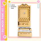 a wooden paint kit, including a wooden cabinet and a wooden drawer, set against a pink and yellow background.