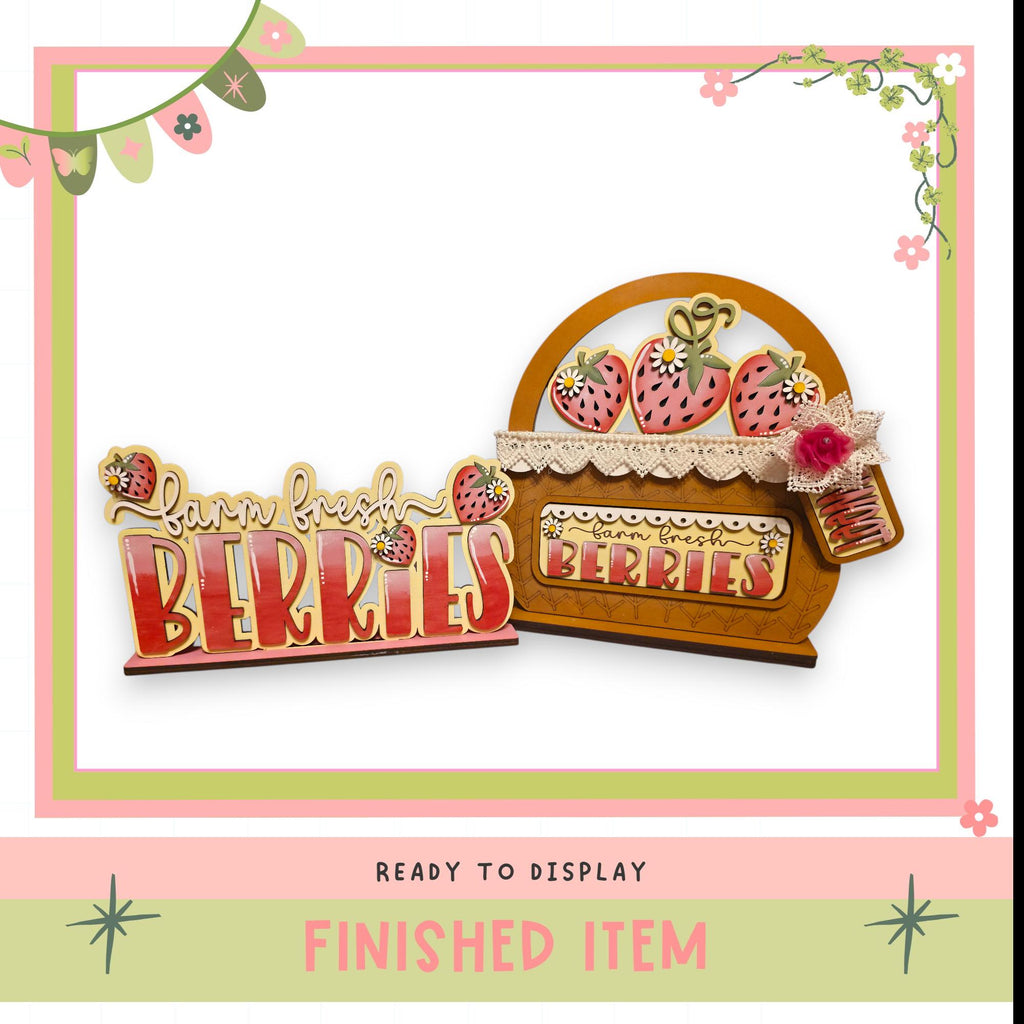 a wooden sign with the word "BERRIES" written on it, along with a basket of strawberries. The sign and basket are displayed in a pink and green frame, and the image is described as a finished item, ready to be displayed.